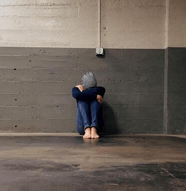 Person sitting alone in a parking garage.